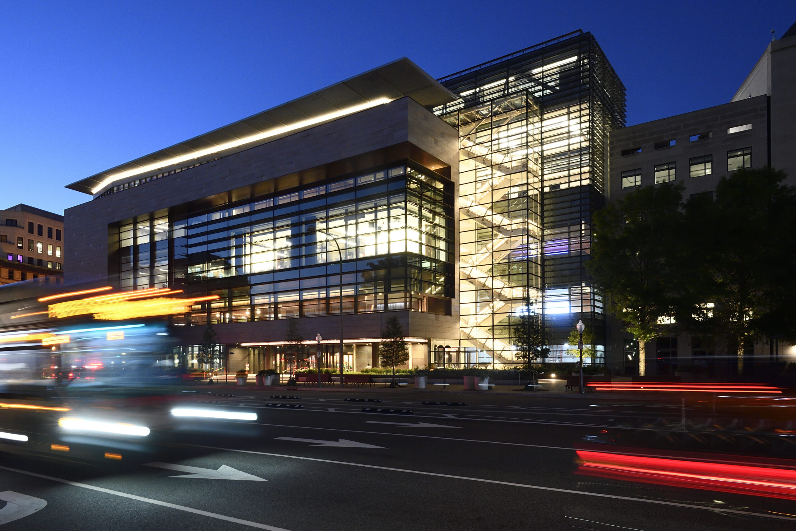 Exterior of building at night, with blurred car lights on the road in front